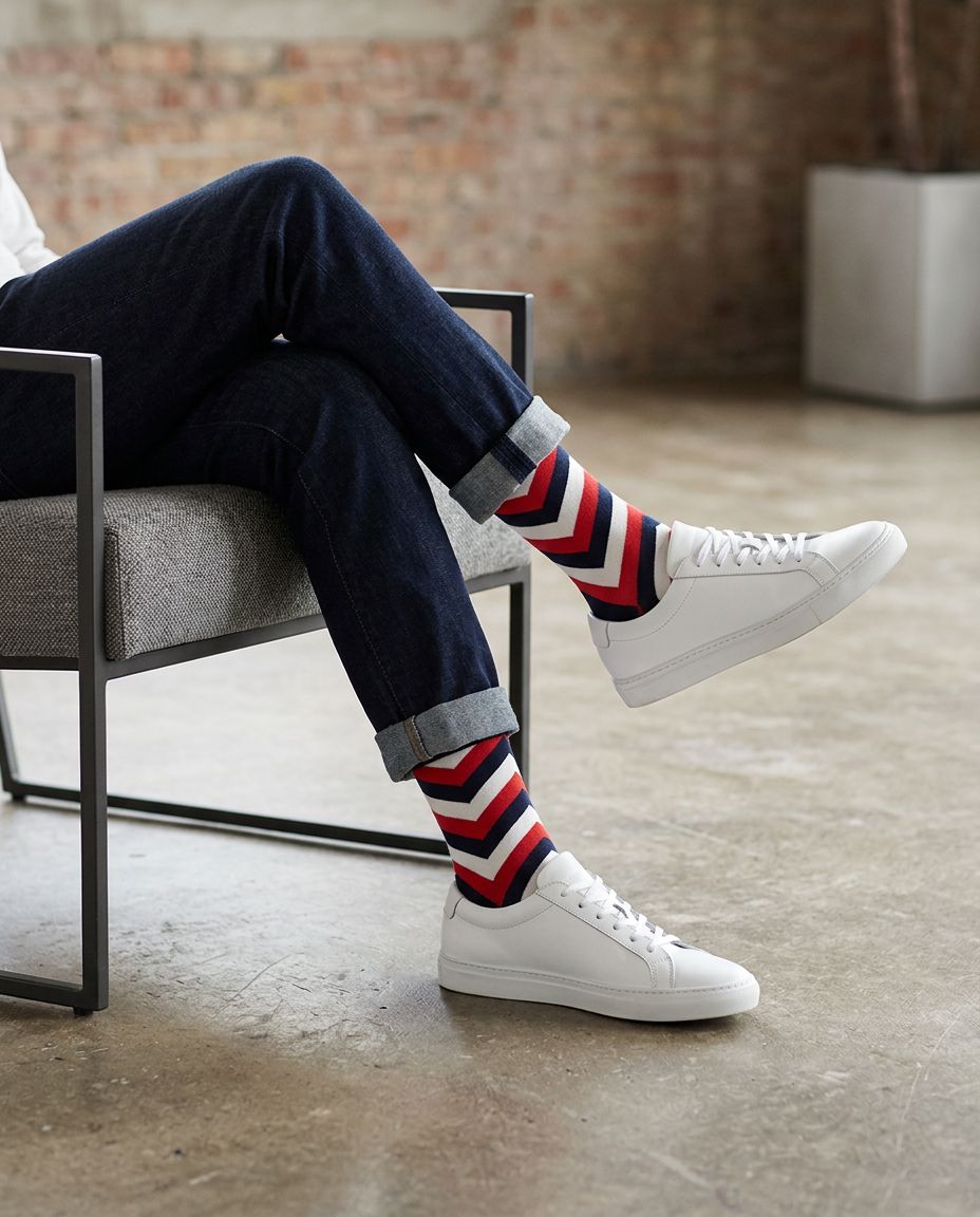 Person wearing red white and navy chevron socks with white sneakers